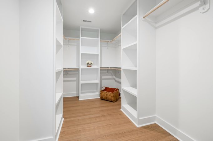 Vestidor Blanco Vestidor amplio y luminoso con estanterías blancas y suelo de madera clara.